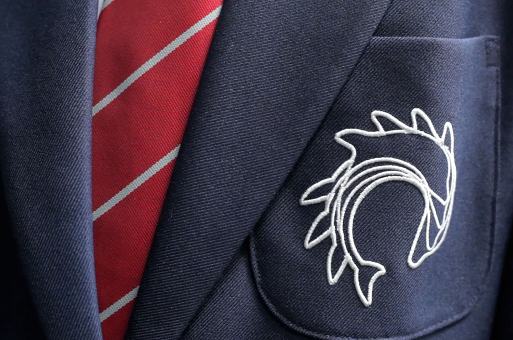 Closeup of a school uniform blazer pocket with an embroidered logo - illustrating ‘U is for Uniform’ in A to Z design for schools blog